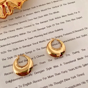 Macro view of gold hollow hoop earrings on book page with smooth polished metal finish