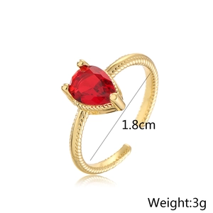 Macro detail of gold plated ring showing pear shaped red gemstone and twisted band texture