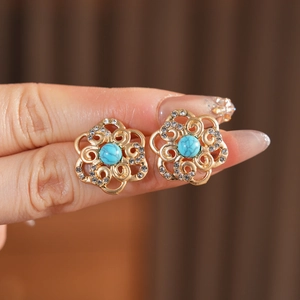 Detailed view of vintage gold hollow flower earrings with turquoise center and rhinestones