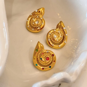 Macro shot of three vintage gold seashell earrings with pearls and colorful gemstones