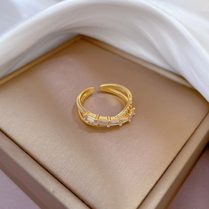 Macro view of gold-plated crossover ring with pavé-set rectangular cubic zirconia gems