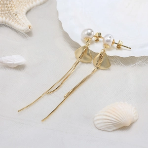 Detail of golden tassel earrings with freshwater pearls and shell ocean theme decor