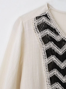 Macro detail of cream V-neck dress featuring vintage black and white crochet lace embroidery