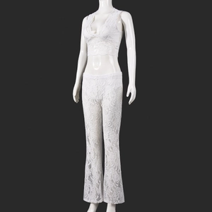 Detailed close-up of white floral lace fabric on a V-neck crop top and flare trousers