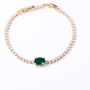 Detail of gold tennis bracelet with large oval green gemstone and square zircon stones