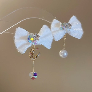 Close-up of bow earrings with pearls, rhinestones, moon and heart charms on a stand