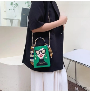 Detail of green box evening bag with cartoon character graphic and gold chain strap