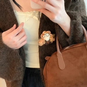 Dettaglio di una spilla a bambola fatta a mano con occhiali su un cardigan marrone scuro