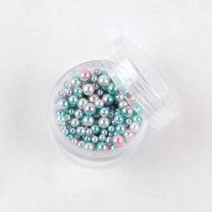 Dettaglio di perle sintetiche iridescenti multicolori in scatola per hobby creativi