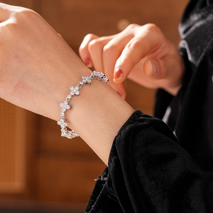 Macro detail of silver flower bracelet featuring zircon pavé settings on a female wrist