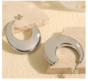 Macro shot of silver C-shaped chunky earrings with mirror polished finish on stone tray