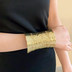 Detail view of wide gold-plated metal cuff featuring vintage embossed floral patterns