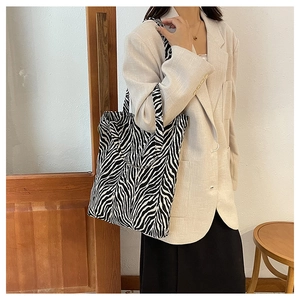 Detailed view of zebra print canvas tote bag carried over the shoulder by a model