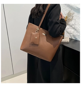 Detail of a brown leather tote bag with small pouch and golden hardware on shoulder