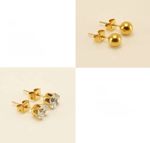 Detailed macro of polished gold stud earrings featuring round ball and zircon claw settings