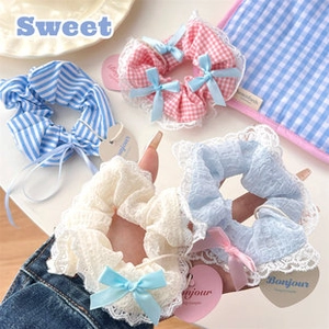 Detail von süßen Stoff-Scrunchies mit Spitzenkanten und Bandschleifen im 4er-Set
