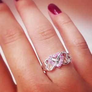 Macro detail of silver heart ring featuring pink cubic zirconia pavé and hollow band