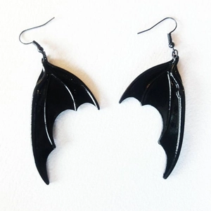 Détail rapproché de boucles d'oreilles gothiques ailes de chauve-souris noires polies