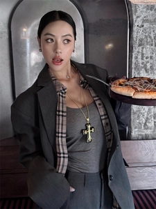 Macro shot of large black resin cross pendant with vintage gold pattern on casual blazer