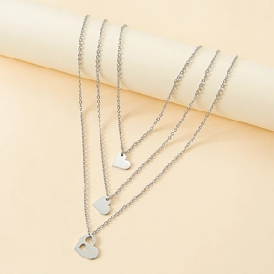 Detailed view of three silver stainless steel necklaces with solid and cutout heart pendants