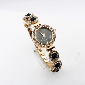 Detail of luxury gold watch with rhinestone bezel and black gemstone bracelet strap