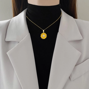 Gold titanium sunflower necklace with crystal core worn by a model in beige blazer