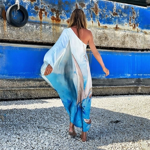 Detail eines One-Shoulder-Maxikleids mit blauem Segelboot-Druck auf Satinstoff