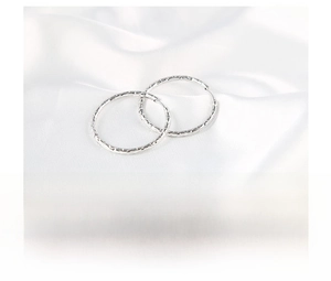 Detail of silver stainless steel hoop earrings with unique hammered textured surface