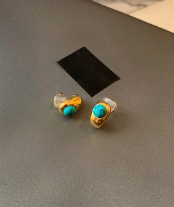Detailed macro view of 18k gold plated turquoise stud earrings with silicone backings