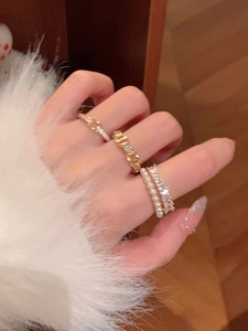 Close-up of stacked gold rings with pearls and zircon stones on a woman's finger