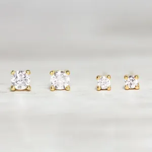 Macro shot of two pairs of 925 sterling silver gold-plated stud earrings with zircon