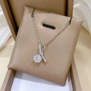 Détail macro du collier argenté avec pendentif au design croisé serti de zircons brillants