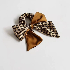 Detail of a velvet bow scrunchie with brown satin and classic houndstooth fabric pattern