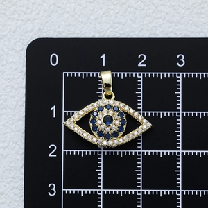 Evil eye pendant in gold finish with blue and clear zircon crystals on a ruler scale