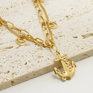 Minimalist double-layer stainless steel anchor bracelet with 18k gold finish on beige stone