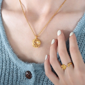 Retro gold sun and moon pendant necklace with matching ring worn on blue knit sweater
