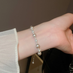 Gros plan d'un bracelet en perles de luxe avec séparateurs sertis de diamants au poignet