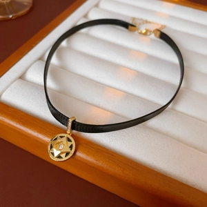 Macro shot of gold star pendant with zircon stone on black textured choker band