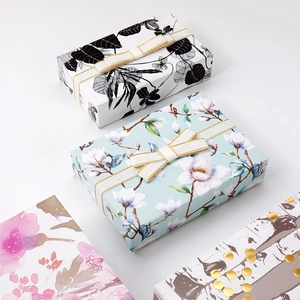Assorted elegant gift boxes featuring floral, leaf, and gold dot patterns with silk ribbons