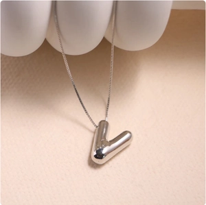 Detailed view of a silver V letter pendant on a box chain with high polish finish