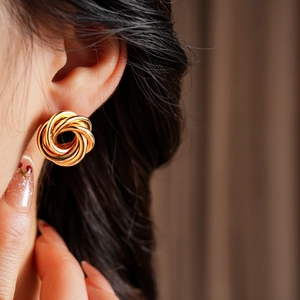 Close-up of a model wearing minimalist golden geometric interlaced hoop earrings