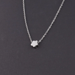 Close-up of a silver minimalist stainless steel necklace with a small floral flower pendant