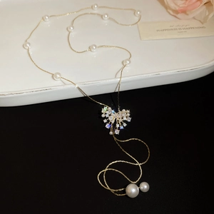 Detail view of 18k gold plated long pearl necklace with zircon pendant on white plate
