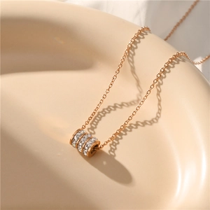 Elegant rose gold cylinder pendant necklace with sparkling zircon pavé on beige surface