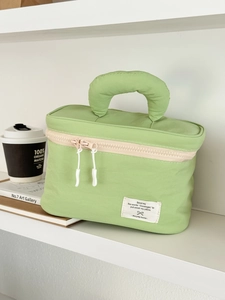 Detail of light green quilted nylon cosmetic bag showing texture and hand strap