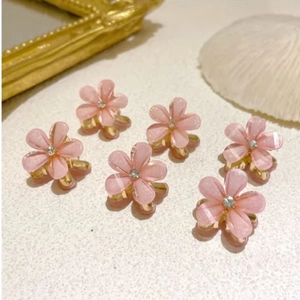 Detail of six pink floral mini hair clips with rhinestones and gold metal claw bases