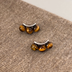 Detailed view of silver hoop earrings with tiger eye stone beads on a knit texture
