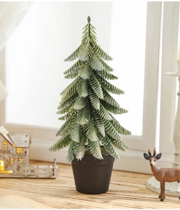 Miniature snow-covered Christmas tree in black pot with gold glitter on a cozy window sill