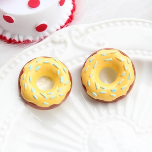 Macro view of chocolate donut charm with yellow frosting and blue sprinkles on a white plate