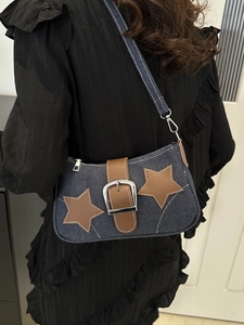 Detailed close-up of blue denim shoulder bag with leather stars and metallic buckle